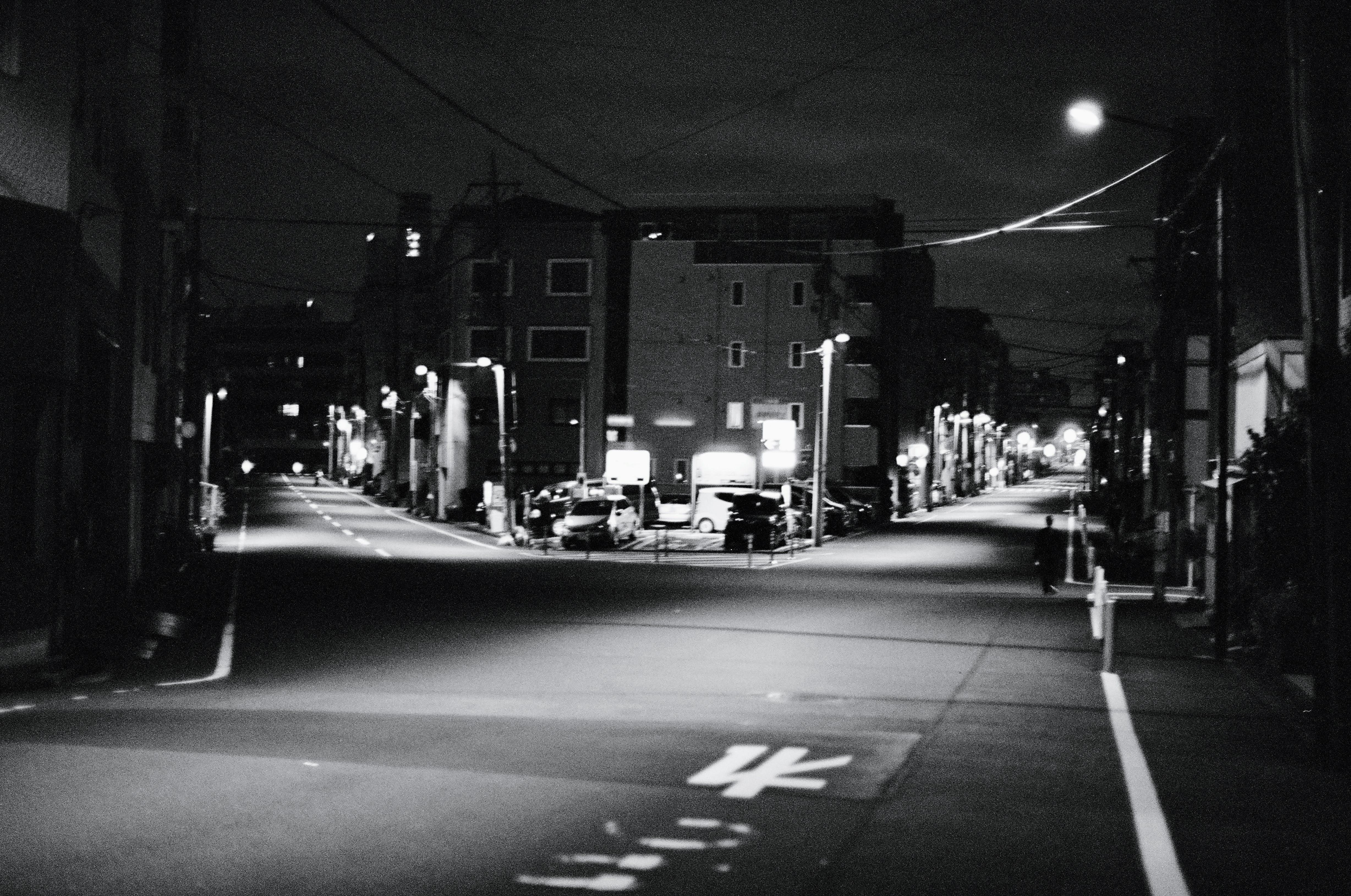 A road forks through a residential neighbourhood. Street lights illuminate the fork in the road.