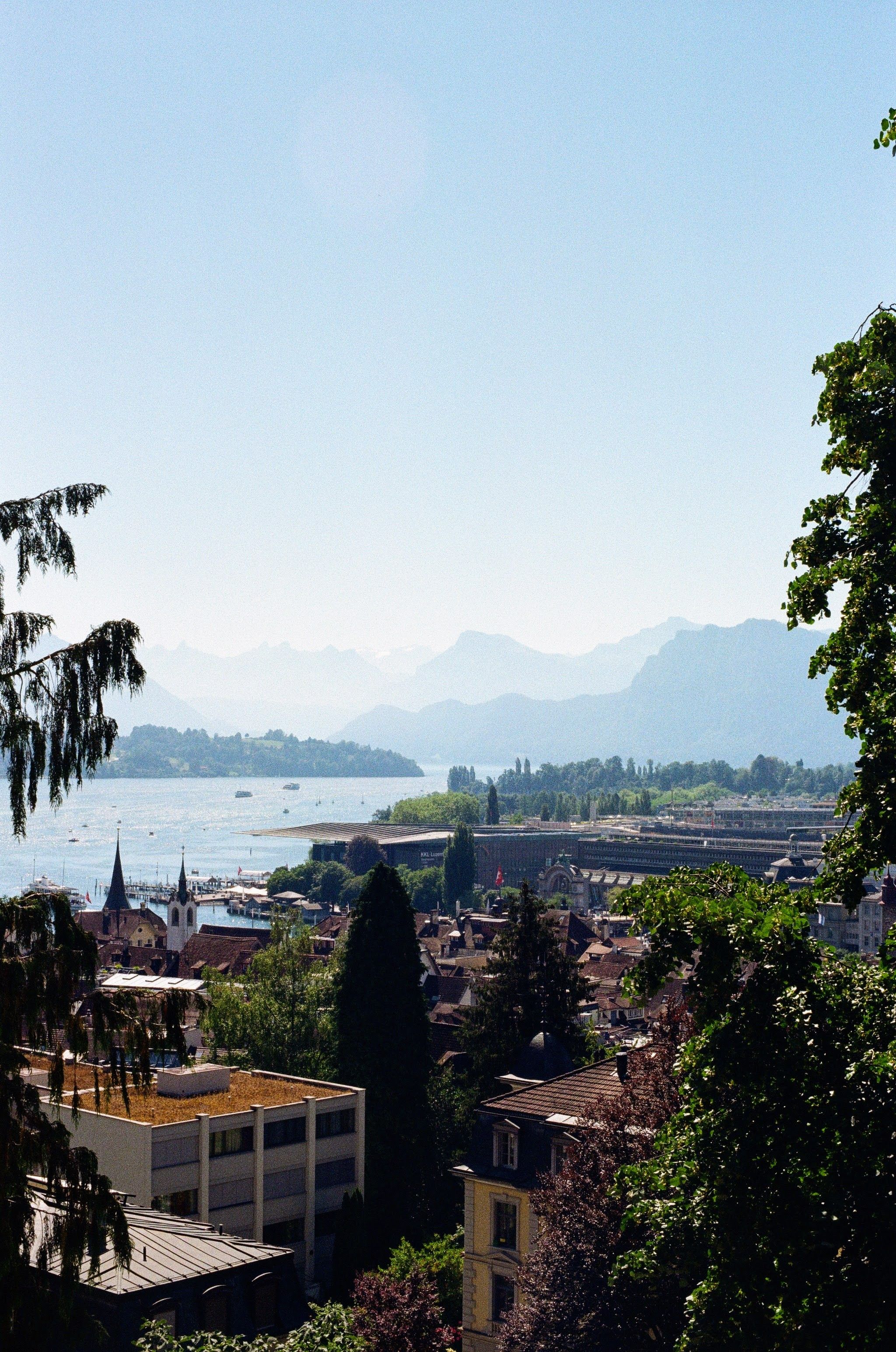 Roofs of the old town of Lucerne, next to a lake. Mountains are in the background.